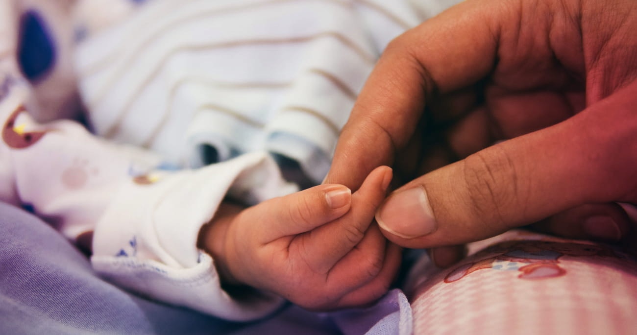 infant child’s hand holding an adult’s hand