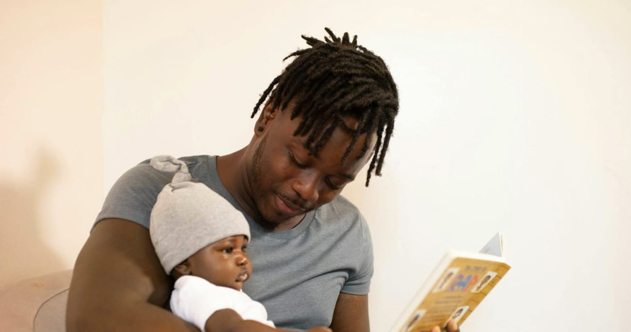 Man holding an infant on his lap and reading