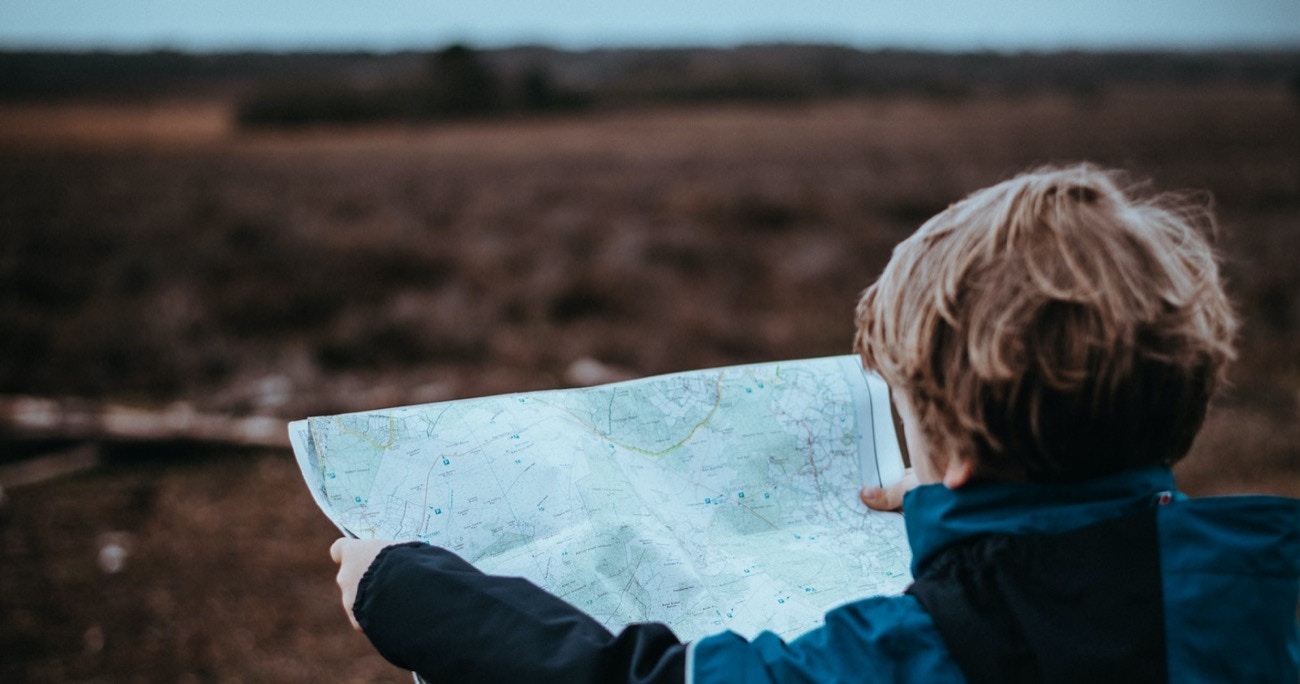 child holding up map of a trail while hiking
