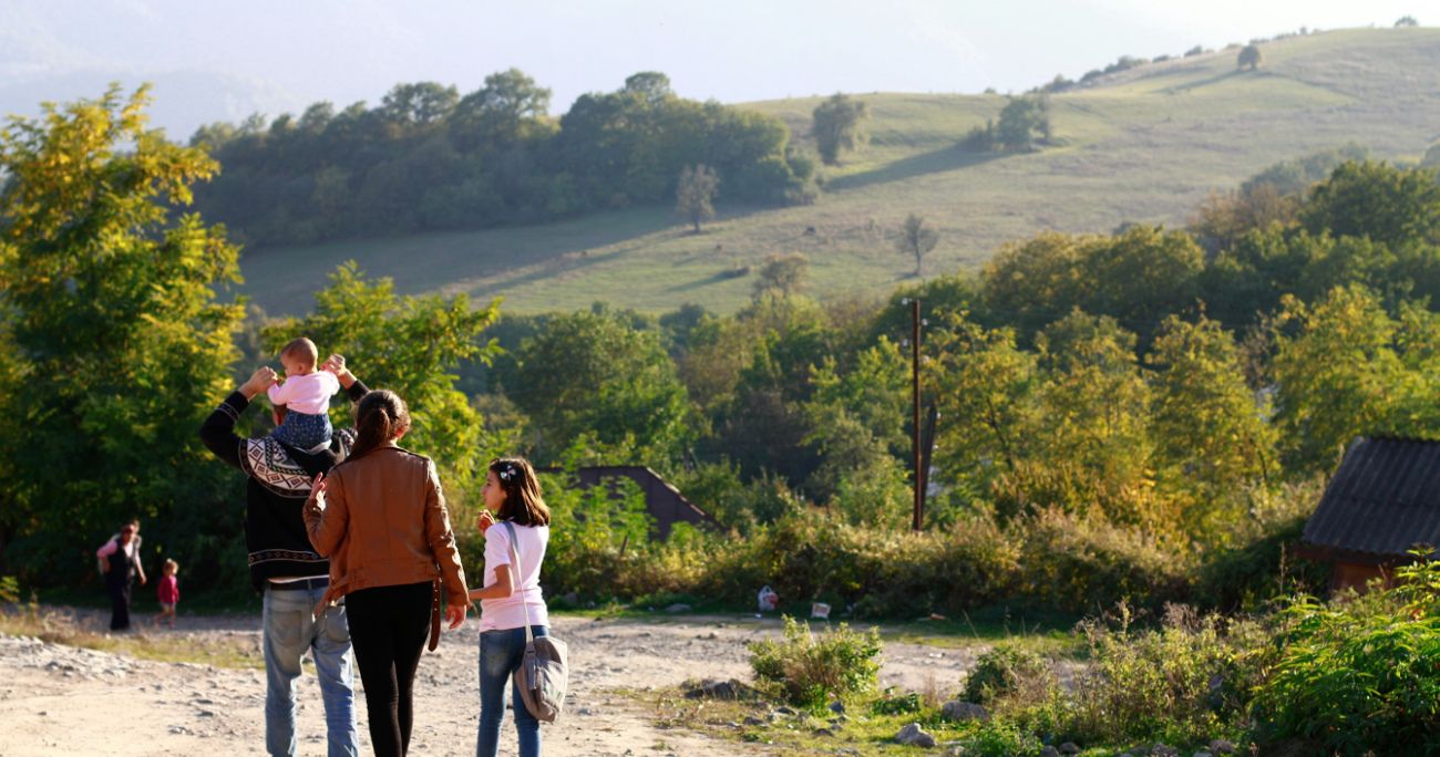 family walking in a village with a hill in the background