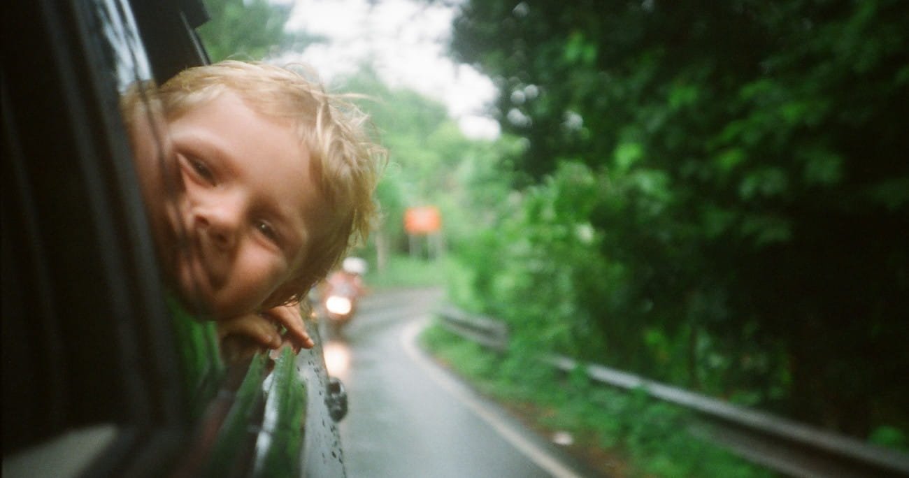 young child looking out a car window while on a trip