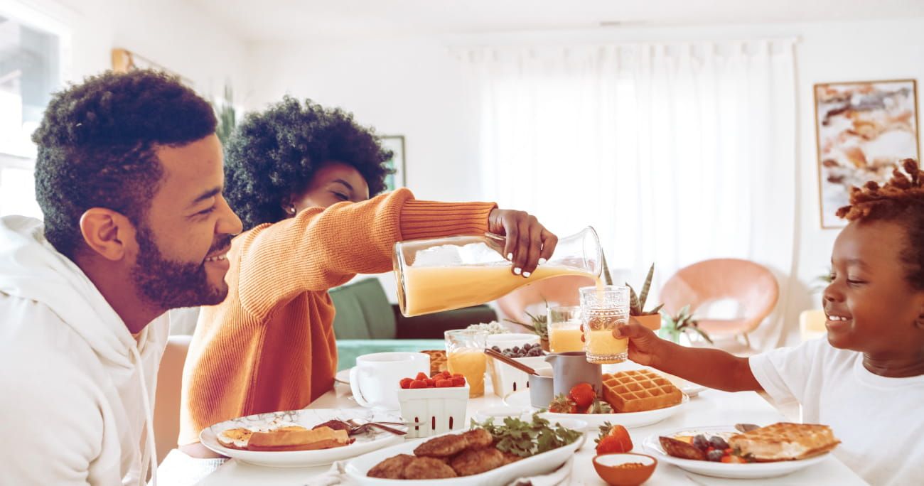 family sharing breakfast as mom pours orange juice for daughter