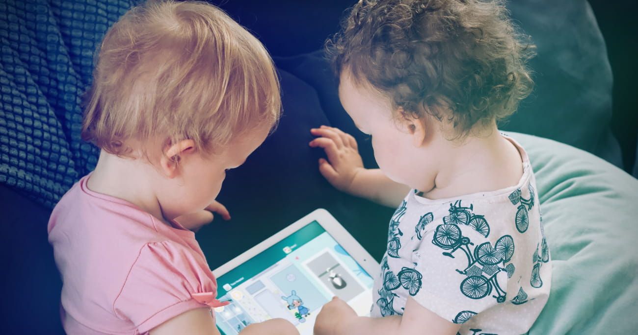 two young toddlers playing on an iPad