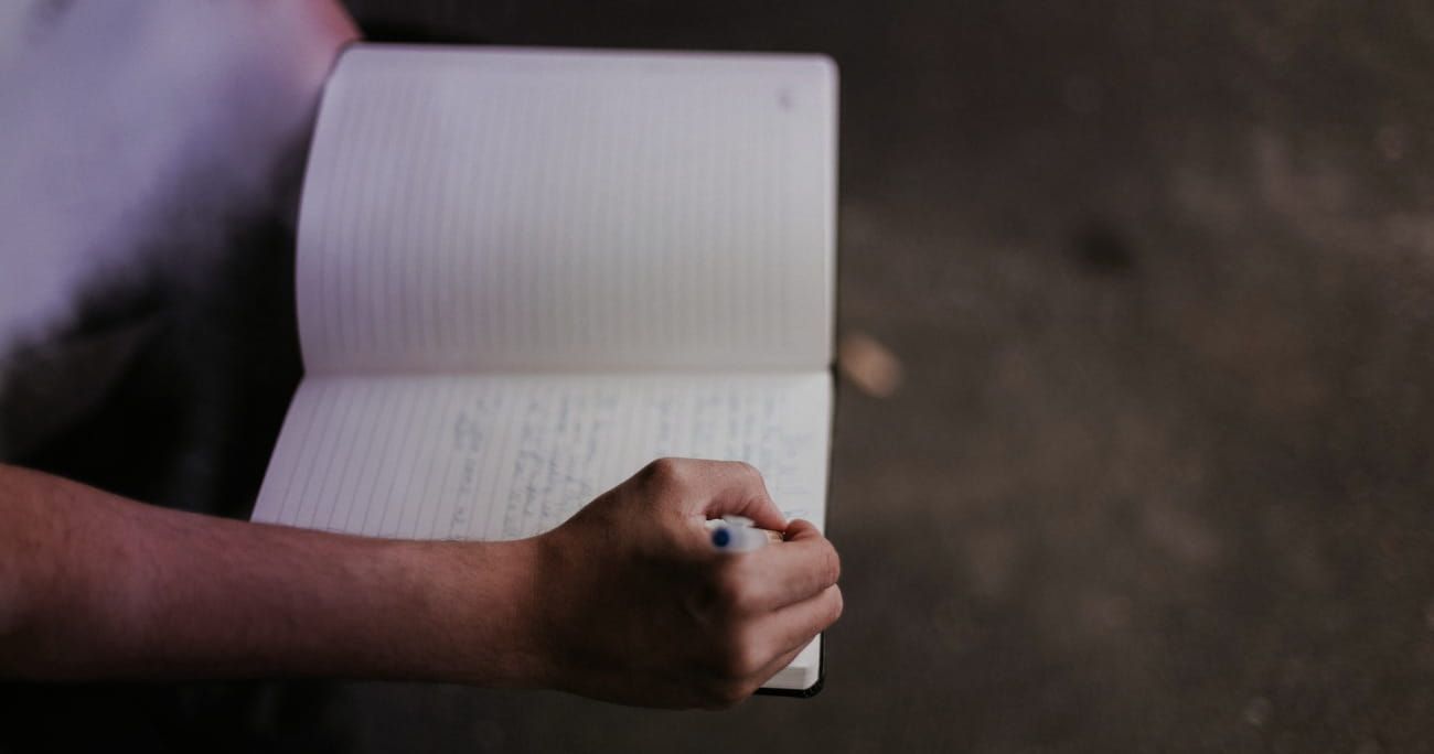 hands holding a journal and pen