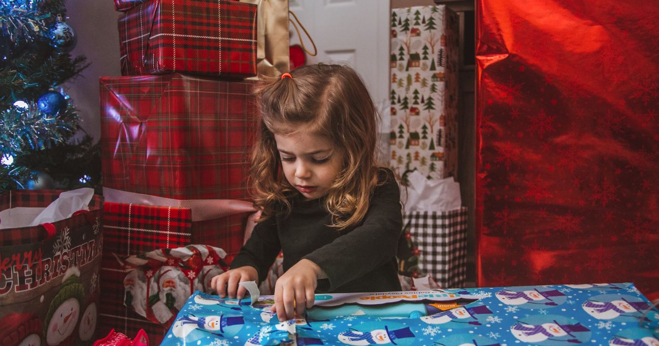 child opening a present in front of a Christmas tree