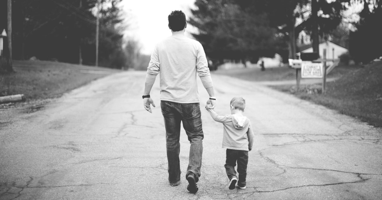 dad holding young son's hand while walking