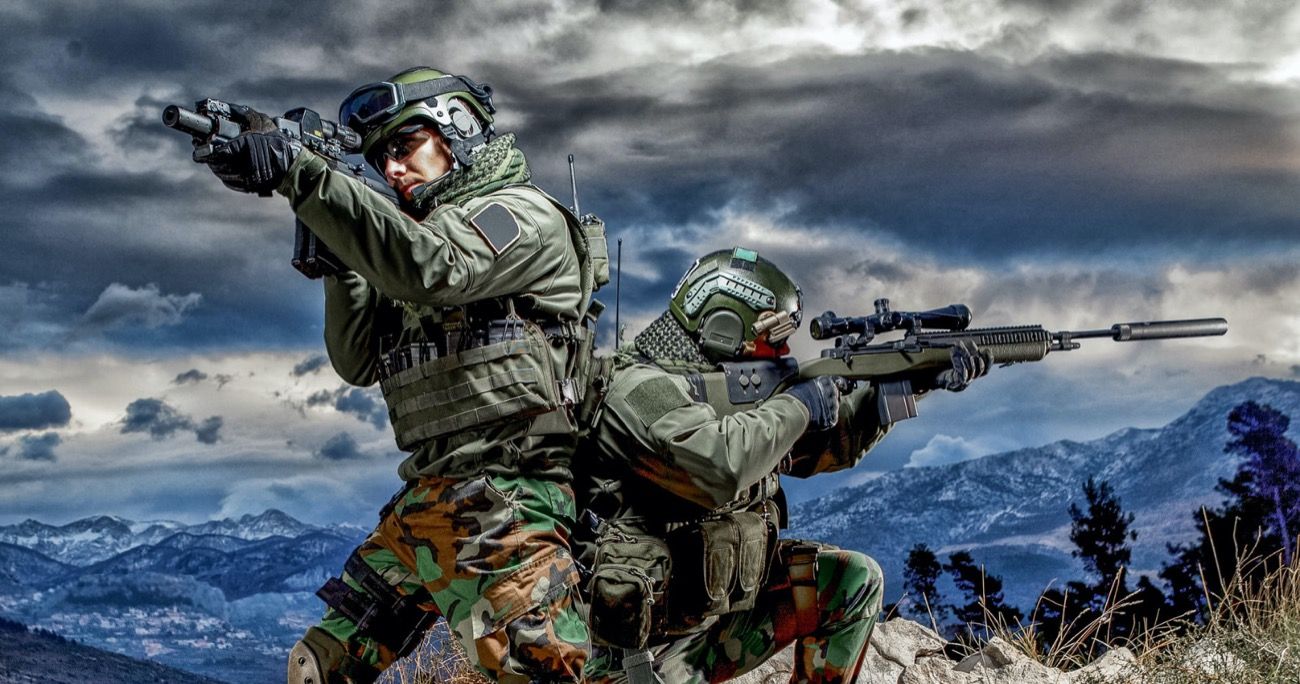 two military people on a mountaintop on the lookout with guns